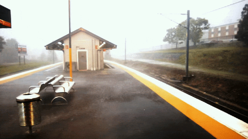 Animated loop of rain sweeping across a train station platform in a storm
